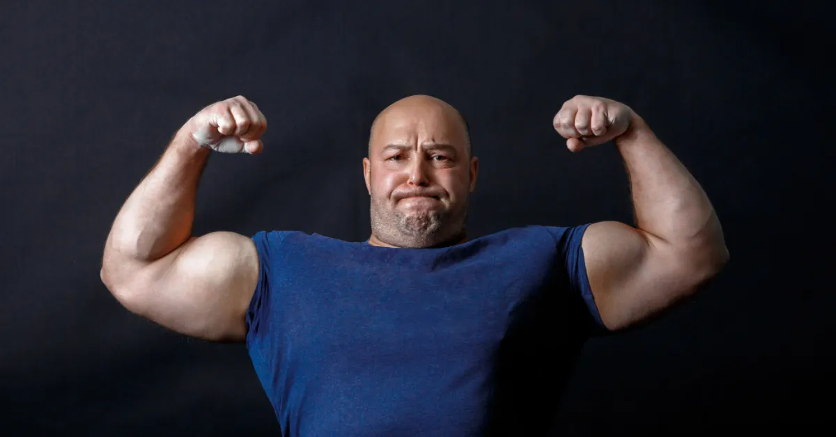 Umięśniony strongman pokazuje bicepsy
